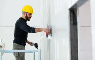 worker plastering gypsum board wall.