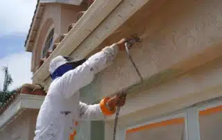 Exterior stucco painter applying fresh coating on a residential wall for repair and finishing quality results